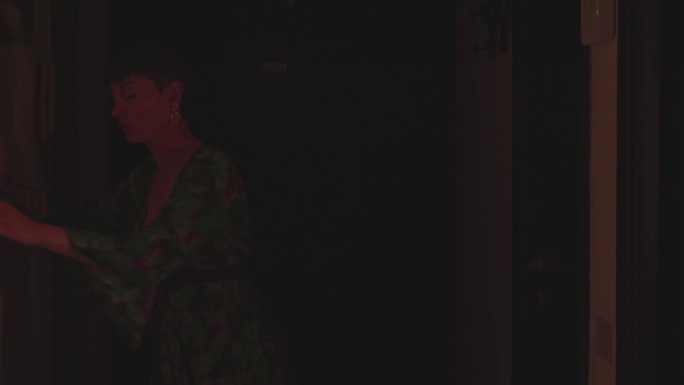 一个喝醉了的女人在黑暗中沿着走廊摸索的慢镜头