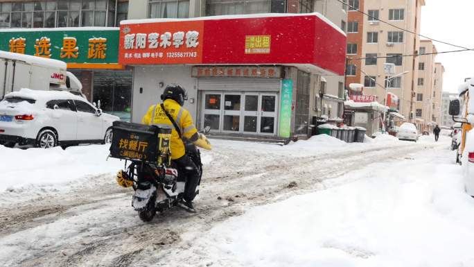 雨雪天外卖骑手取餐送餐在马路上骑行