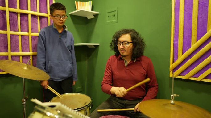 中年男子在录音棚教他的学生男孩架子鼓