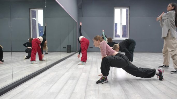 女孩跳舞。集体练习，跳舞前的集体热身课。六个女孩站在镜子前做腿部肌肉伸展运动。