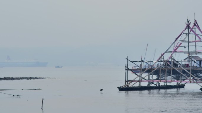 白天，一艘小船驶过停靠在南榜渔村港口附近的大型渡轮和渔船