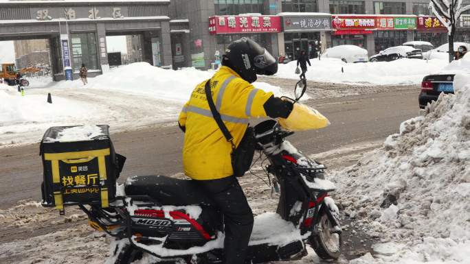 雨雪天外卖骑手取餐送餐在马路上骑行