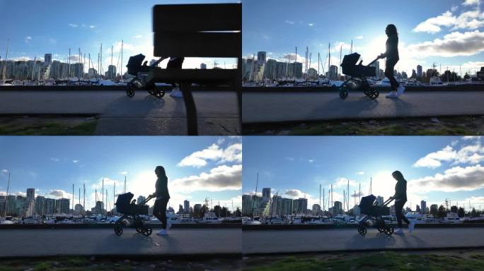 赤柱公园海堤上推着婴儿车的母亲。阳光灿烂的日子