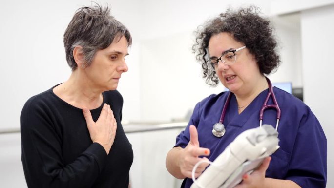 医生向一位妇女解释便携式紧急除颤器的工作原理