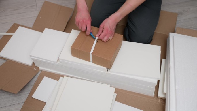 工人为家具组装打开装有家具板的箱子。搬家后拆纸箱。