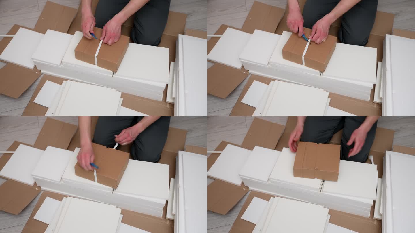 工人为家具组装打开装有家具板的箱子。搬家后拆纸箱。