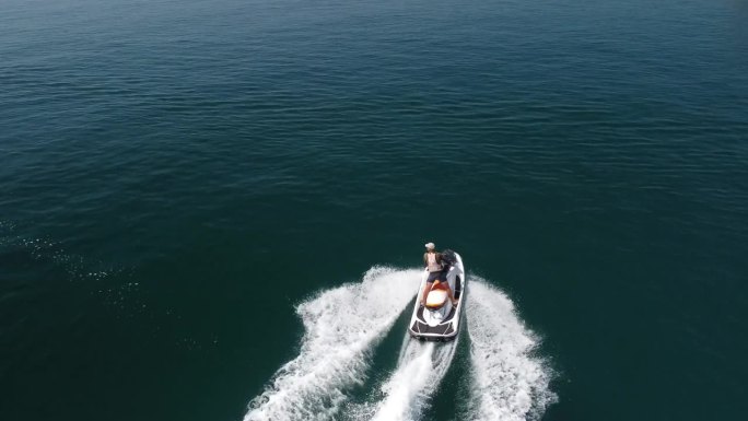 空中俯瞰的水泡沫痕迹与漂亮的深蓝色海洋阴影。在一艘动力强劲的小型摩托艇后面，平静的海面上有一条美丽的