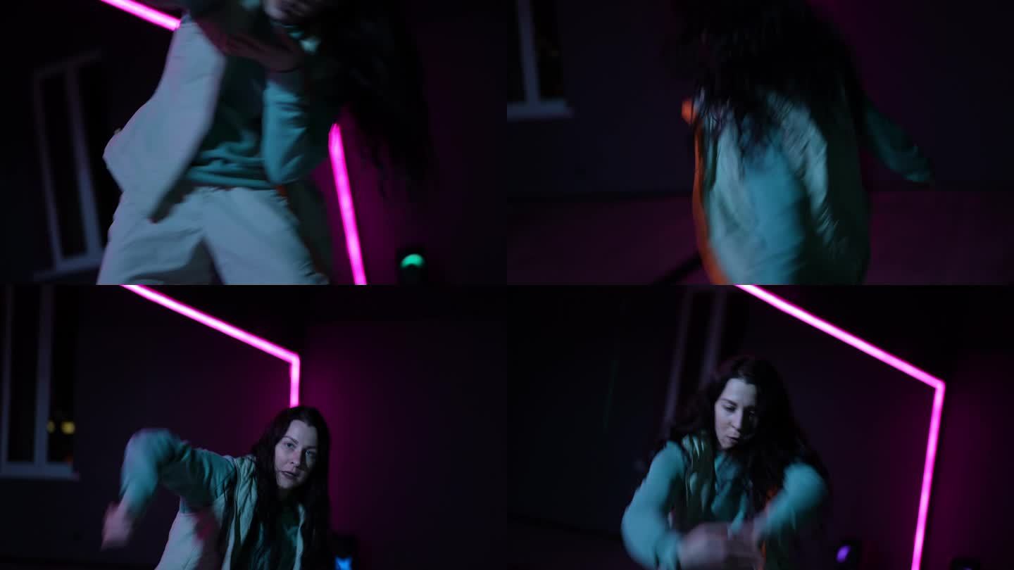 住相机。特写镜头。一个女孩在霓虹灯照亮的黑暗舞蹈大厅里跳着充满活力的嘻哈舞。