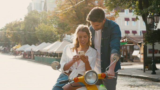 女人向男人展示从摩托车上用手机拍摄的照片