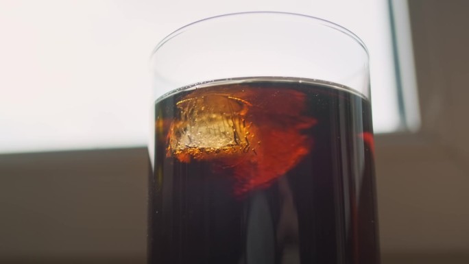 可乐鸡尾酒杯和冰块。特写，冰的结构。威士忌朗姆酒可乐。它靠窗而立。