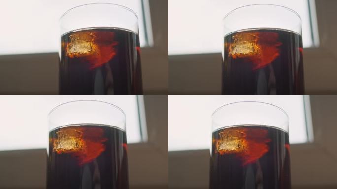 可乐鸡尾酒杯和冰块。特写，冰的结构。威士忌朗姆酒可乐。它靠窗而立。