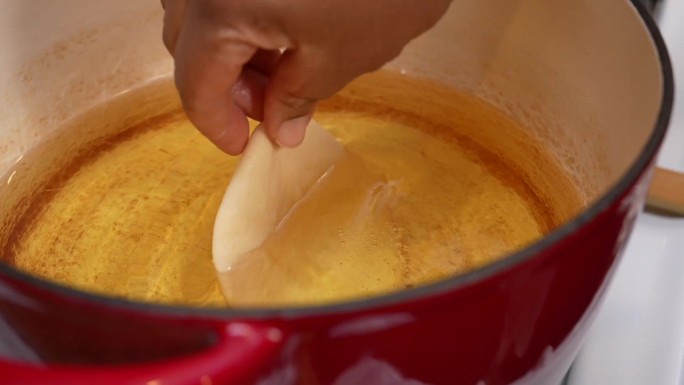 将生面团放入热油中制作印度巴图拉面包- Chana Masala系列