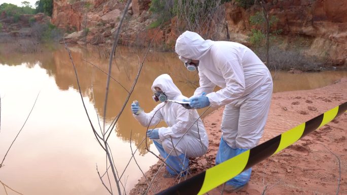 科学家们穿着化学防护设备和辐射防护服收集放射性污染水的样本。
