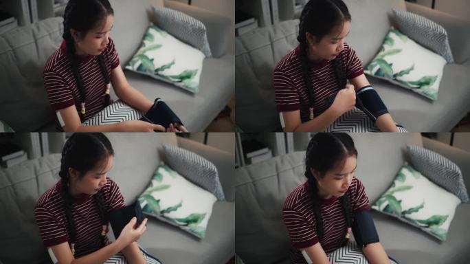 一名携带血糖传感器的亚洲少女正在家中使用数字血压仪