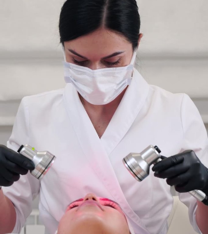 美容师使用LED治疗面部年轻化。一名妇女在护肤诊所接受红光治疗。在美容院增加胶原蛋白，减少皱纹。无创