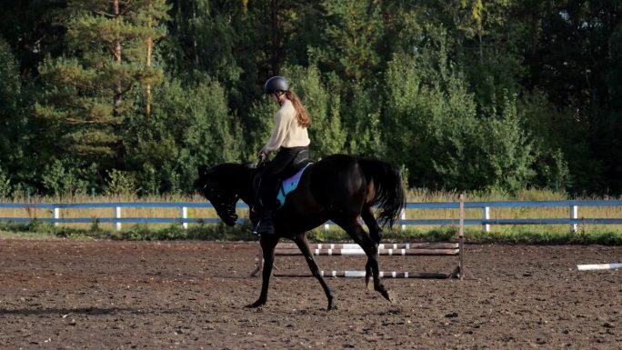 一个骑马的年轻女子，在马术俱乐部里骑马。在训练场上骑马的女骑手。在马术俱乐部里，一位女士骑着马