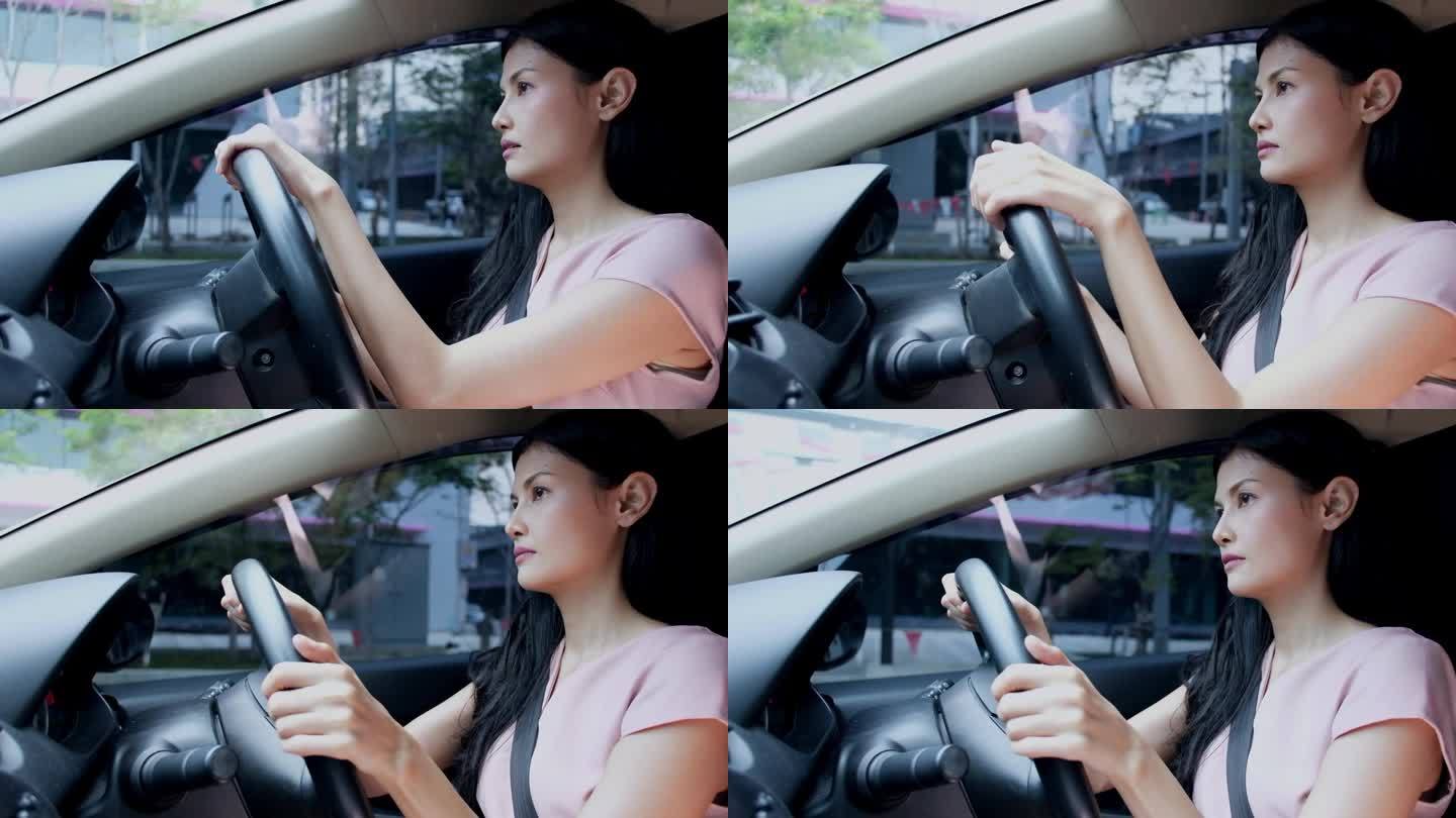 亚洲女司机穿着休闲装坐在车里，在城市开车时看起来很直。快乐的女商人透过窗户看着马路，开车在城市里转悠