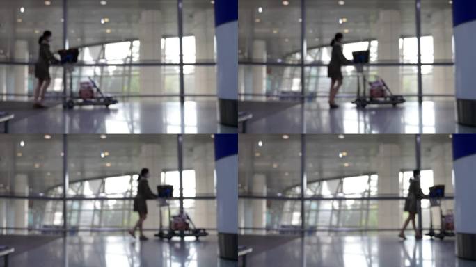 模糊的画面:一个女人推着行李车穿过候机楼，慢镜头