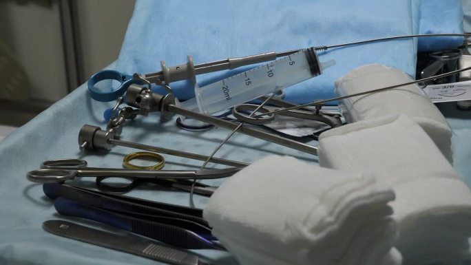 外科医生准备开始手术，蓝色背景的无菌器械躺在手术台上。手术器械概念。