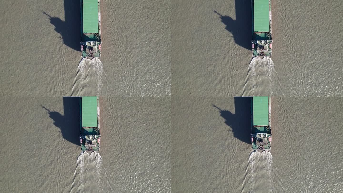 在阳光明媚的日子里，货船在河上航行的高角度视图，它的影子在水面上，无人机俯视图，4k实时镜头。