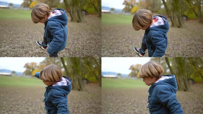 秋天，一个小男孩在公园外抬脚检查脏鞋子。小孩踩便便