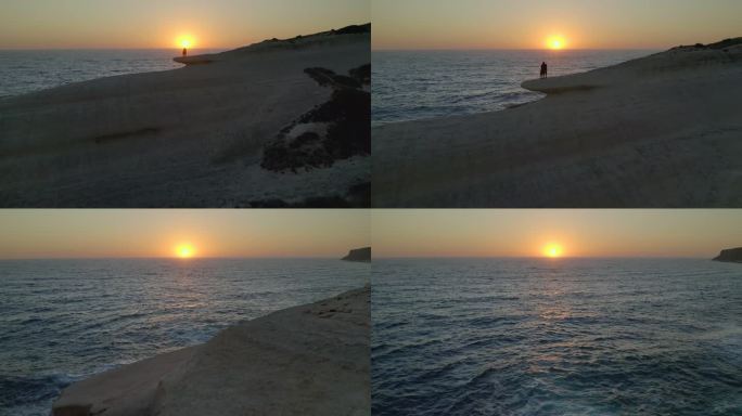 无人机拍摄的一对情侣在意大利撒丁岛苏留岛和萨伊德岛奇妙的地质构造中拥抱在一起，日落时太阳在地平线上