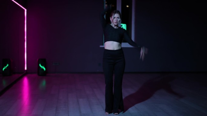 住相机。在霓虹灯照亮的黑暗舞蹈大厅里跳舞的女人。富有表现力、活跃的Waacking舞蹈。