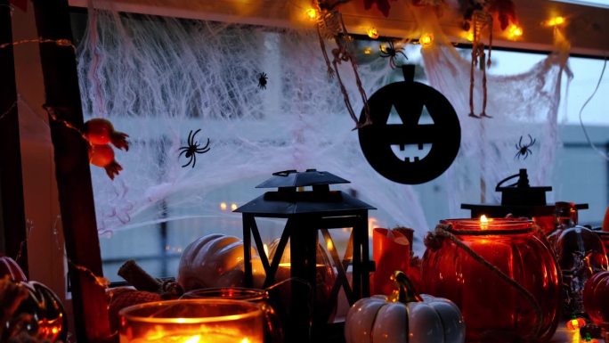 万圣节窗台上的节日装饰——南瓜、杰克灯笼、骷髅头、蜘蛛网、蜘蛛、骷髅、蜡烛和花环——一种舒适而可怕的