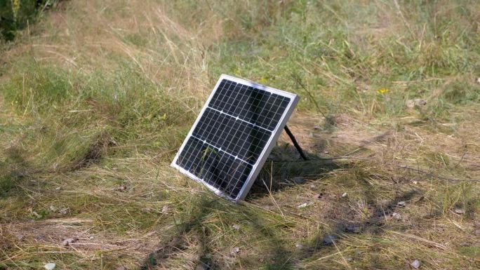 一个小型便携式光伏太阳能电池板安装在草地上的自然