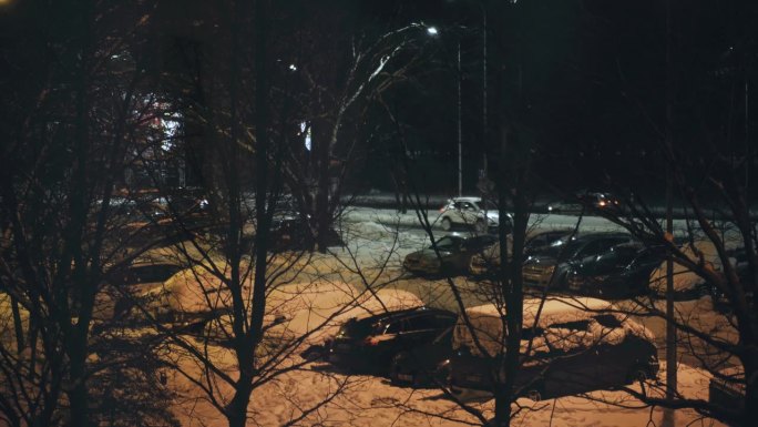 窗外白雪覆盖的汽车和傍晚路上的汽车。
