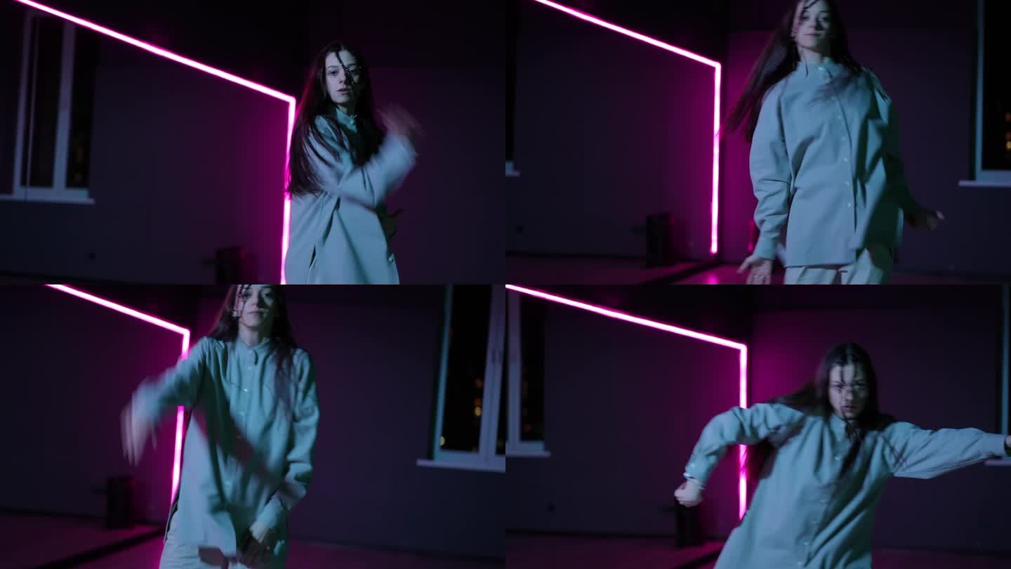 住相机。一个女孩在霓虹灯照亮的黑暗舞蹈大厅里跳舞。动感现代舞与霹雳舞的元素。