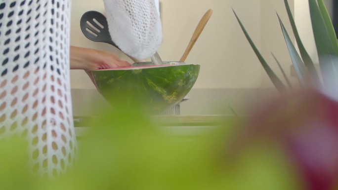 一个女人在厨房用一把大刀切西瓜。缓慢的运动。