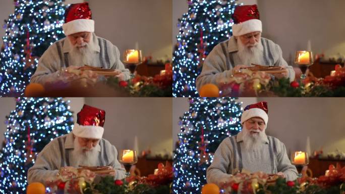 一位留着胡子、戴着圣诞帽的老人坐在桌旁。他从圣诞餐桌上拿起馅饼，看了看，闻了闻，很满意。