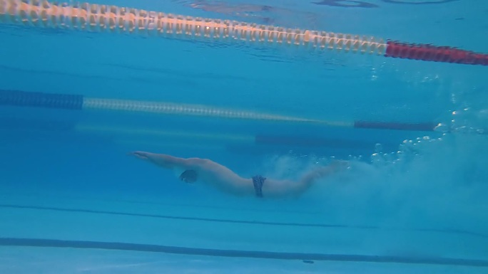 水下镜头，肌肉发达的职业游泳男运动员跳水，跳入泳池。准备好赢得冠军。