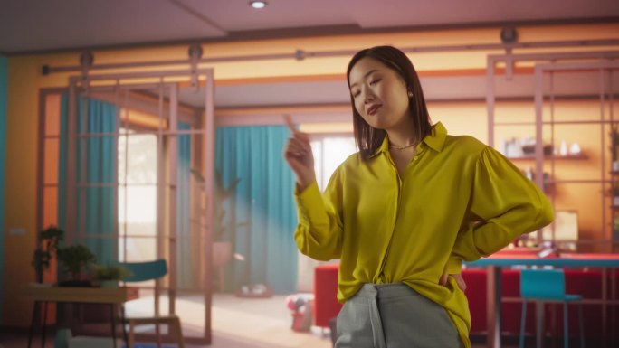 美丽的亚洲女人的手势，仿佛与AR平台互动，滚动和选择，而站在彩色公寓。快乐女性用高科技网购