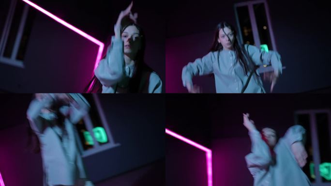 住相机。一个女孩在黑暗的舞蹈大厅里用霓虹灯照亮的镜子跳着充满活力的现代舞。