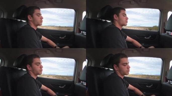 一个疲惫的男人，一个在汽车后座睡觉的乘客，他正乘坐一辆汽车行驶在内华达州沙漠的高速公路上