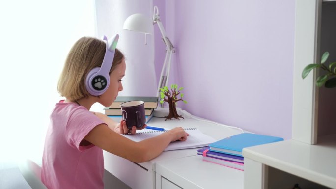 戴着耳机的小女孩在桌前做作业