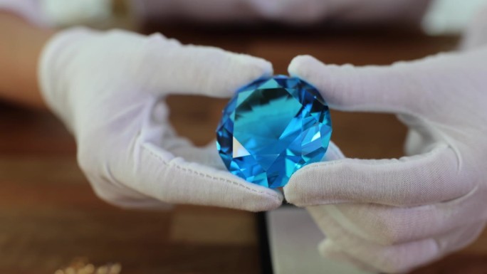 珠宝商戴着手套，手里拿着一颗蓝色的大钻石