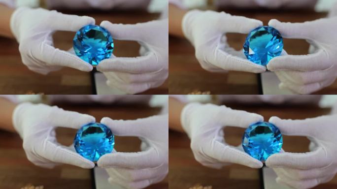 珠宝商戴着手套，手里拿着一颗蓝色的大钻石