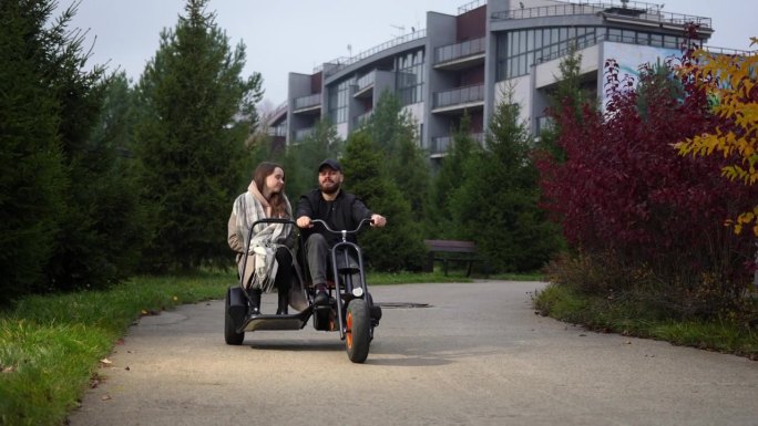 一对夫妇在公园里骑双座三轮车。骑自行车、出租车在城市里旅行