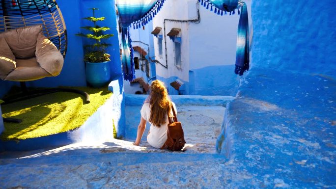 女游客坐在舍夫沙万的蓝色城市旅游，游览摩洛哥旅游