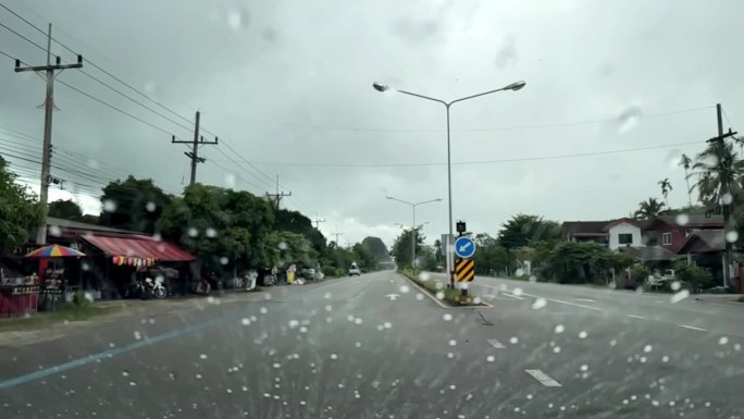 下雨天驾驶的慢动作镜头，选择性聚焦在挡风玻璃上的雨滴。