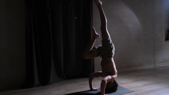 一个赤裸上身的年轻人正在瑜伽房里做瑜伽