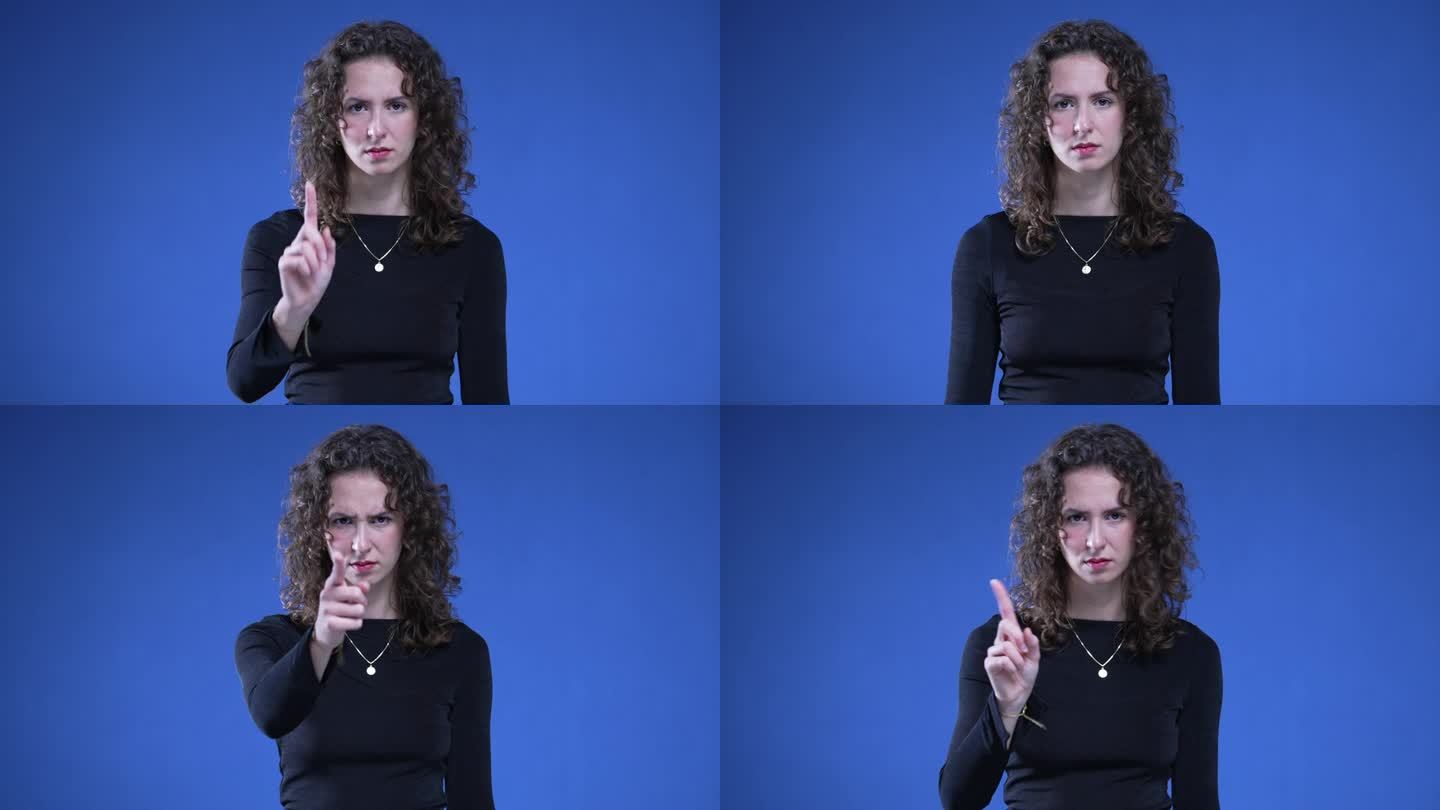 一名女子站在蓝色背景上，指着镜头，用不赞成的手势晃动手指，表示“不”。不喜欢接近的人拒绝了提议