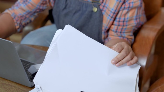 选定的重点是老年咖啡店老板的围裙，工作在一叠纸，账单，付款与笔记本电脑在桌子上。商店关门后做会计的高
