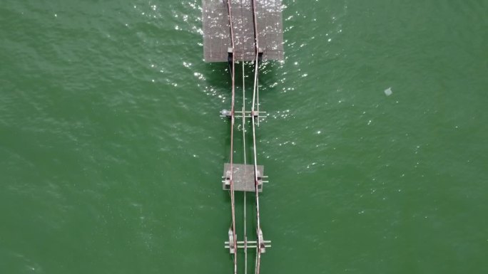 高架的视角显示出宁静的海面上破旧的木桥