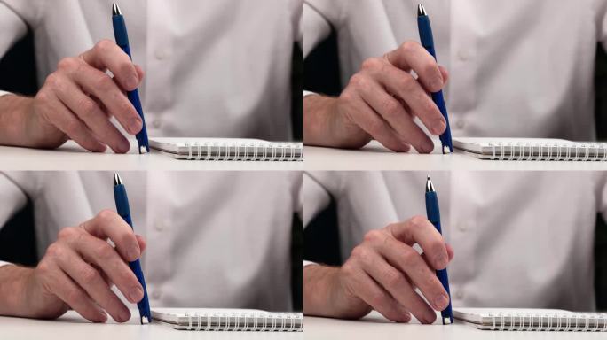 用圆珠笔敲打桌面特写。男人若有所思地敲了敲笔记本旁边的桌子上的笔。