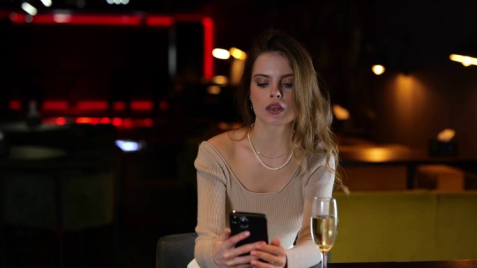 年轻漂亮的女人坐在餐厅里看留言。惊讶的女士看着手机屏幕。生活方式的概念。真正的时间。