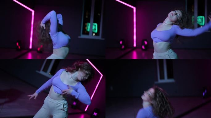 住相机。一名舞者在舞蹈大厅里用霓虹灯照亮的镜子熟练地跳着现代舞。